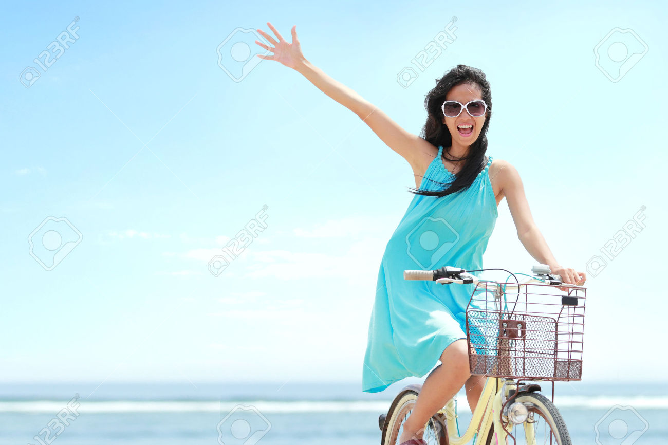 27775406-donna-spensierata-divertirsi-e-sorridente-in-sella-a-bicicletta-in-spiaggia-Archivio-Fotografico.jpg